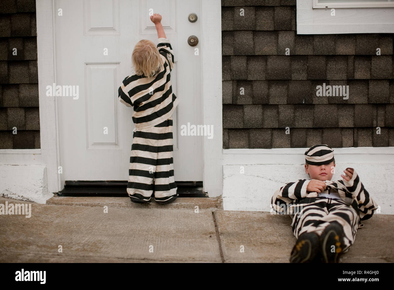 Two boys dressed in prison stripes checking to see if anyone is home Stock Photo