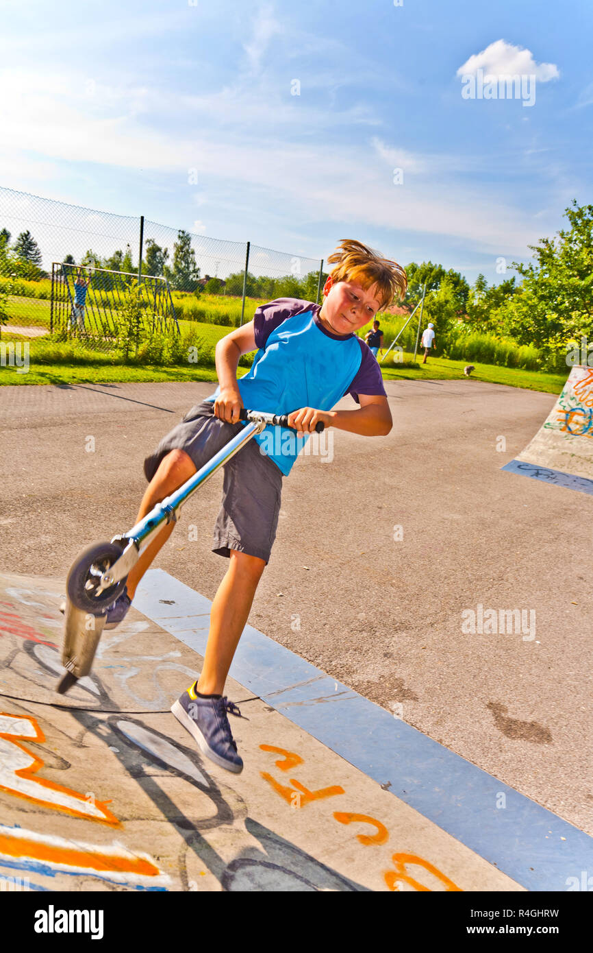 boy is jumping with scooter in pipe Stock Photo
