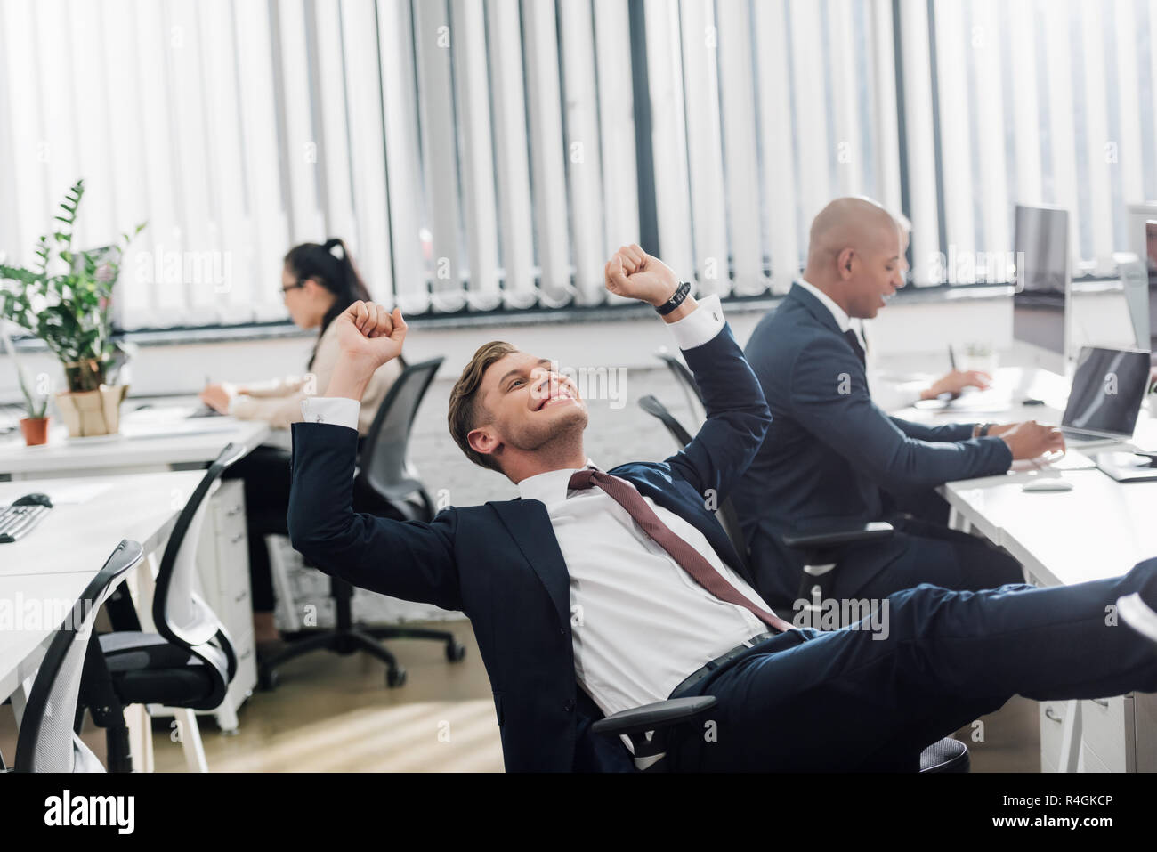 happy young businessman triumphing while working with colleagues in