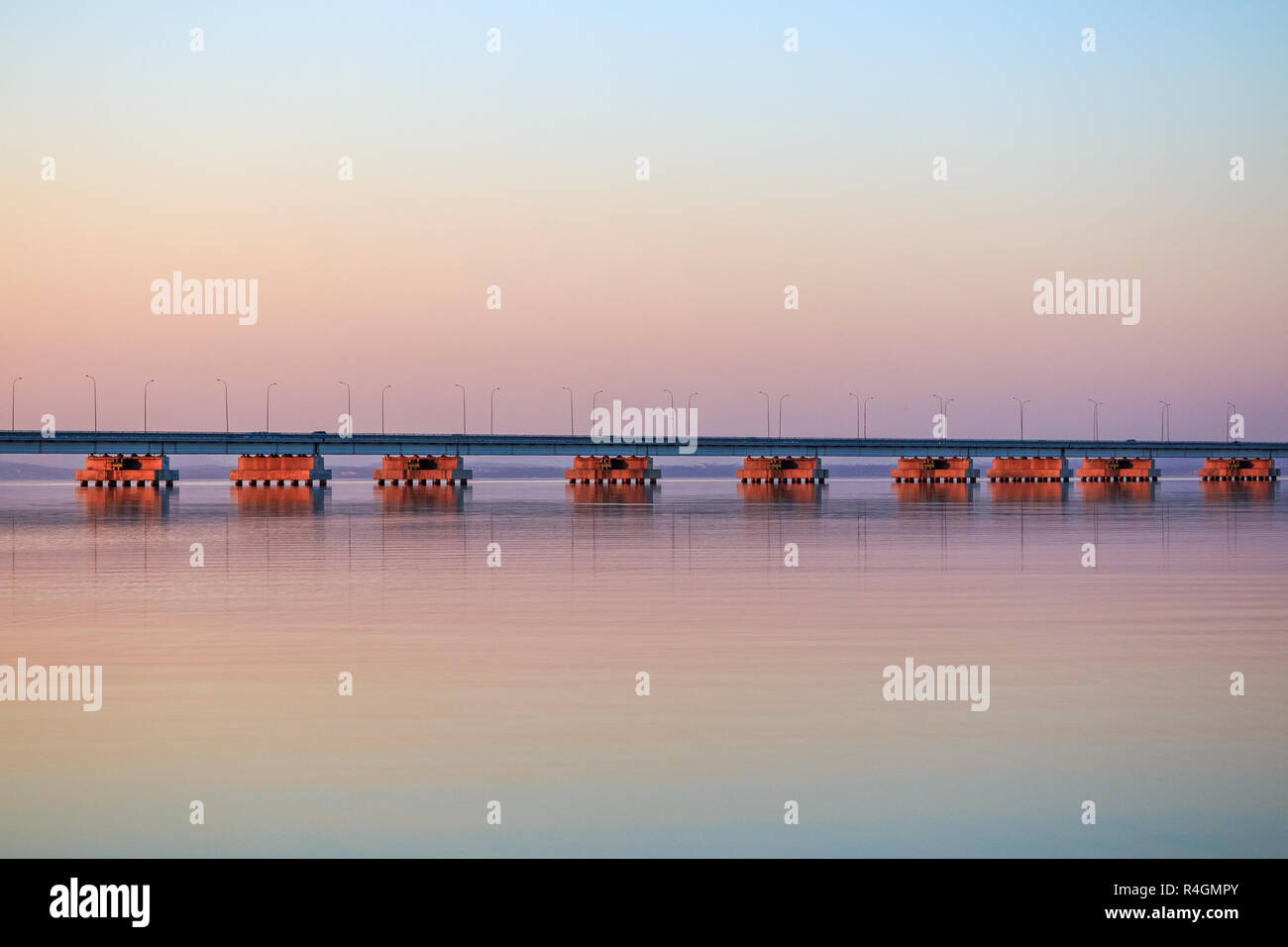 Low water bridge from Sedanka to the De Friz peninsula across the Amur Bay of Primorsky Krai Russia against the background of a red sunset sky. Far Ea Stock Photo