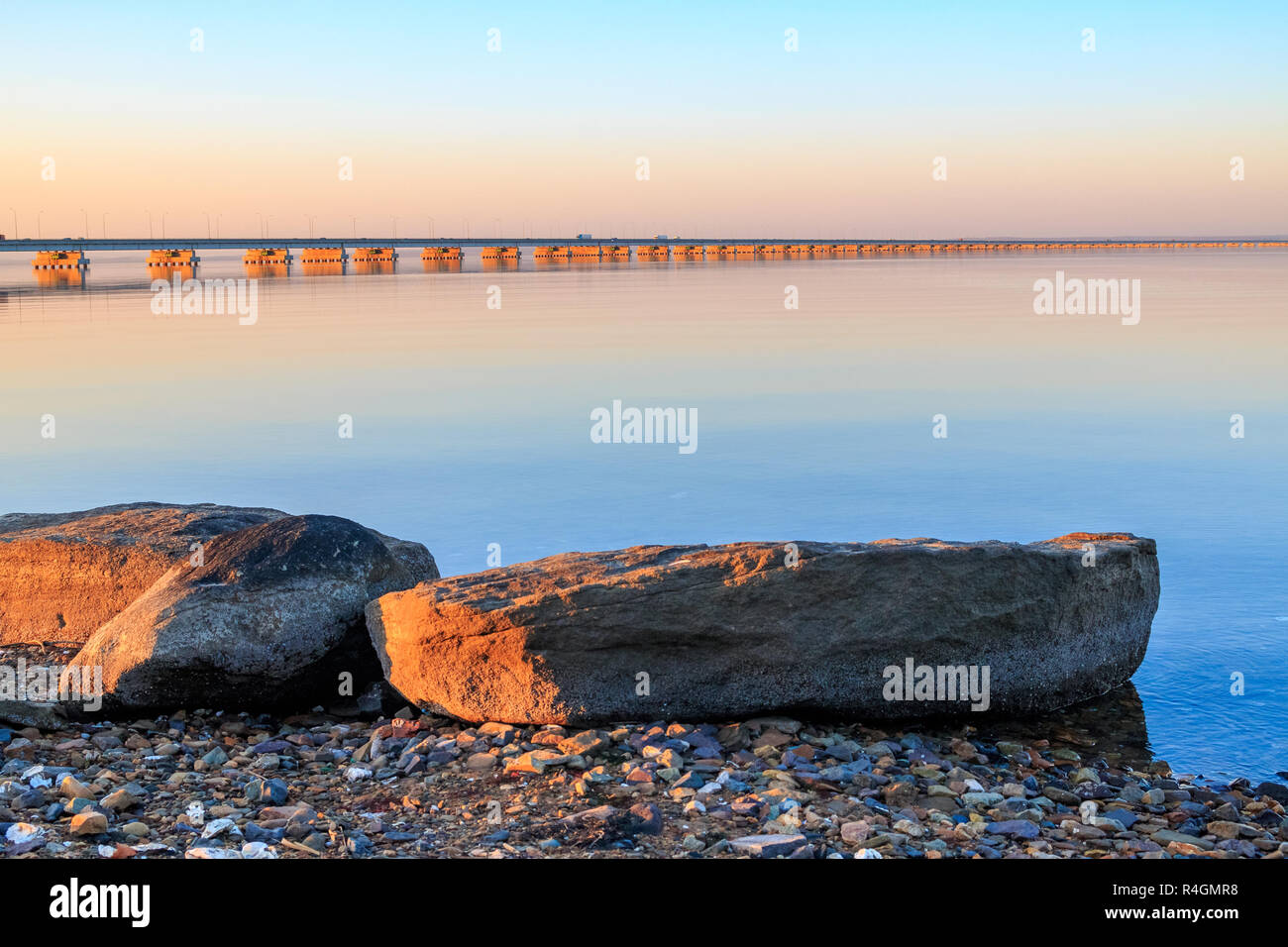 Low water bridge from Sedanka to the De Friz peninsula across the Amur Bay of Primorsky Krai Russia against the background of a red sunset sky. Far Ea Stock Photo