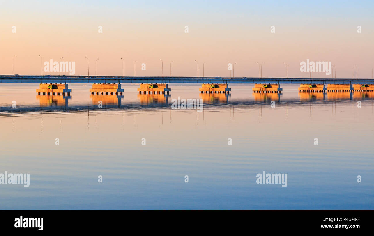 Low water bridge from Sedanka to the De Friz peninsula across the Amur Bay of Primorsky Krai Russia against the background of a red sunset sky. Far Ea Stock Photo