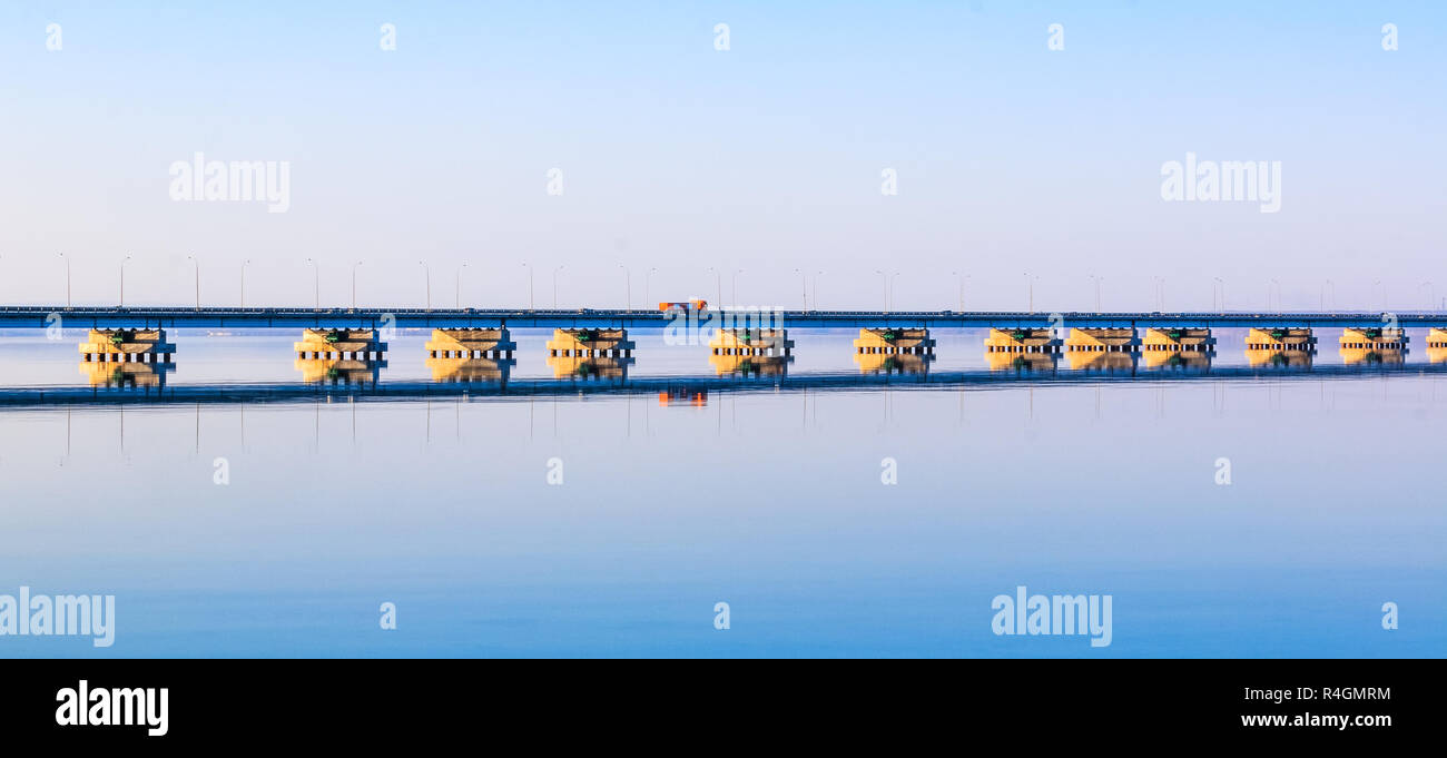 Low water bridge from Sedanka to the De Friz peninsula across the Amur Bay of Primorsky Krai Russia against the background of a red sunset sky. Far Ea Stock Photo