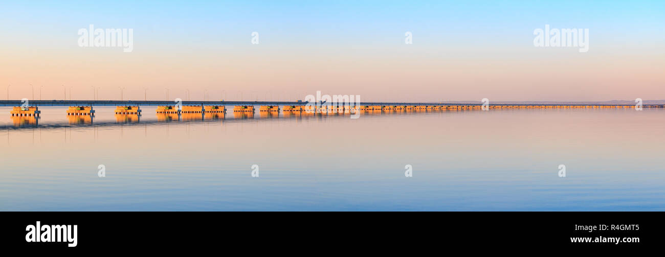 Low water bridge from Sedanka to the De Friz peninsula across the Amur Bay of Primorsky Krai Russia against the background of a red sunset sky. Far Ea Stock Photo