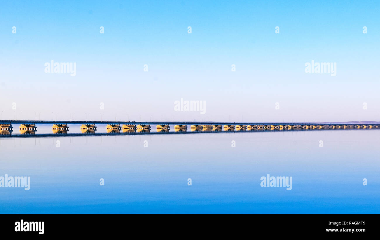 Low water bridge from Sedanka to the De Friz peninsula across the Amur Bay of Primorsky Krai Russia against the background of a red sunset sky. Far Ea Stock Photo