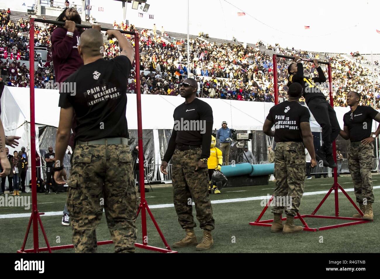 Event attendees from both Alabama A&M University and Alabama State University compete against each other in a Marine Corps pull-up challenge during the Magic City Classic, a 77-year-old college football rivalry between the two largest historically black universities in Alabama, in Birmingham, Oct. 27, 2018. The Marine Corps participates in the Magic City Classic to foster a positive relationship with the community and illustrate a parallel between the indelible fighting spirit of the Marines and the athletes who compete in the classic. Stock Photo