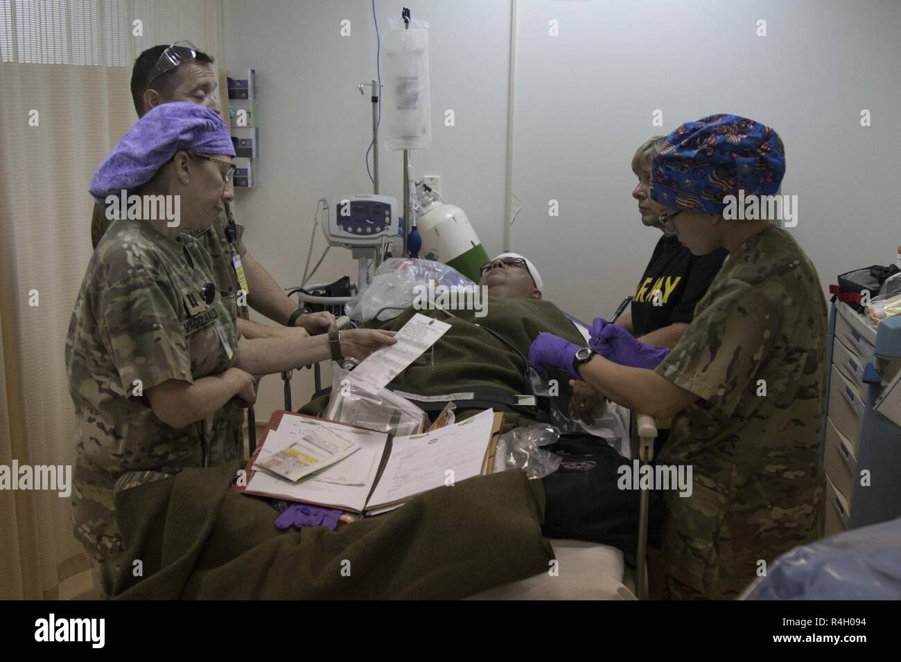 Staff from the 452nd Combat Support Hospital evaluate a casualty's injuries and discuss how to best treat him during a mass casualty exercise at Camp Arifjan, Kuwait, Sept. 26, 2018. The cooperation between first responders and medical personnel are imperative to saving lives Stock Photo