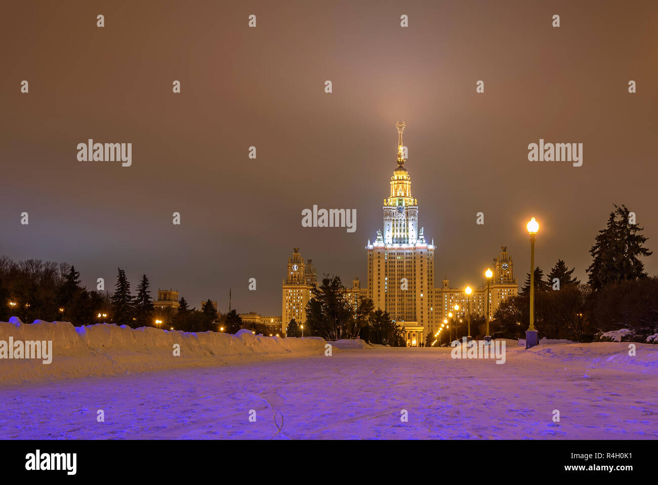 Beautiful night winter view with the main building of Moscow State University, alley, street lights and snow with blue light Stock Photo