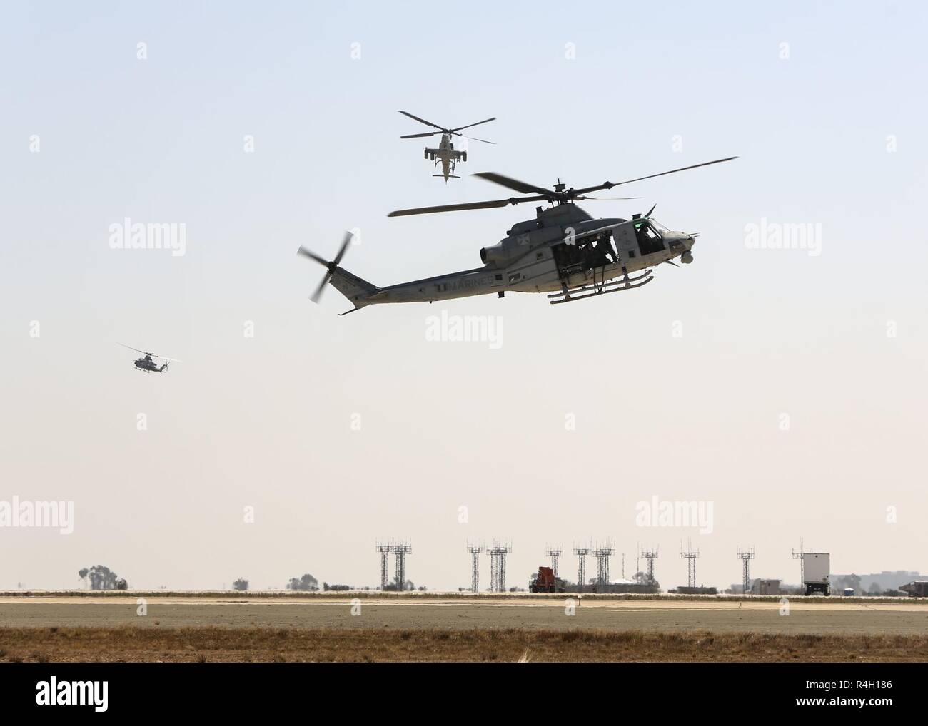 A UH-1Y Huey hovers over the flight line as two AH-1Z Vipers provide close air support during the Marine Air Ground Task Force demonstration at the 2018 Marine Corps Air Station Miramar Air Show on MCAS Miramar, Calif., Sept. 28. This years air show honors '100 years of women in the Marine Corps' by featuring several performances and displays that highlight the accomplishments and milestones women have made since the first female enlistee, Olpha May Johnson, who joined the service in 1918. Stock Photo
