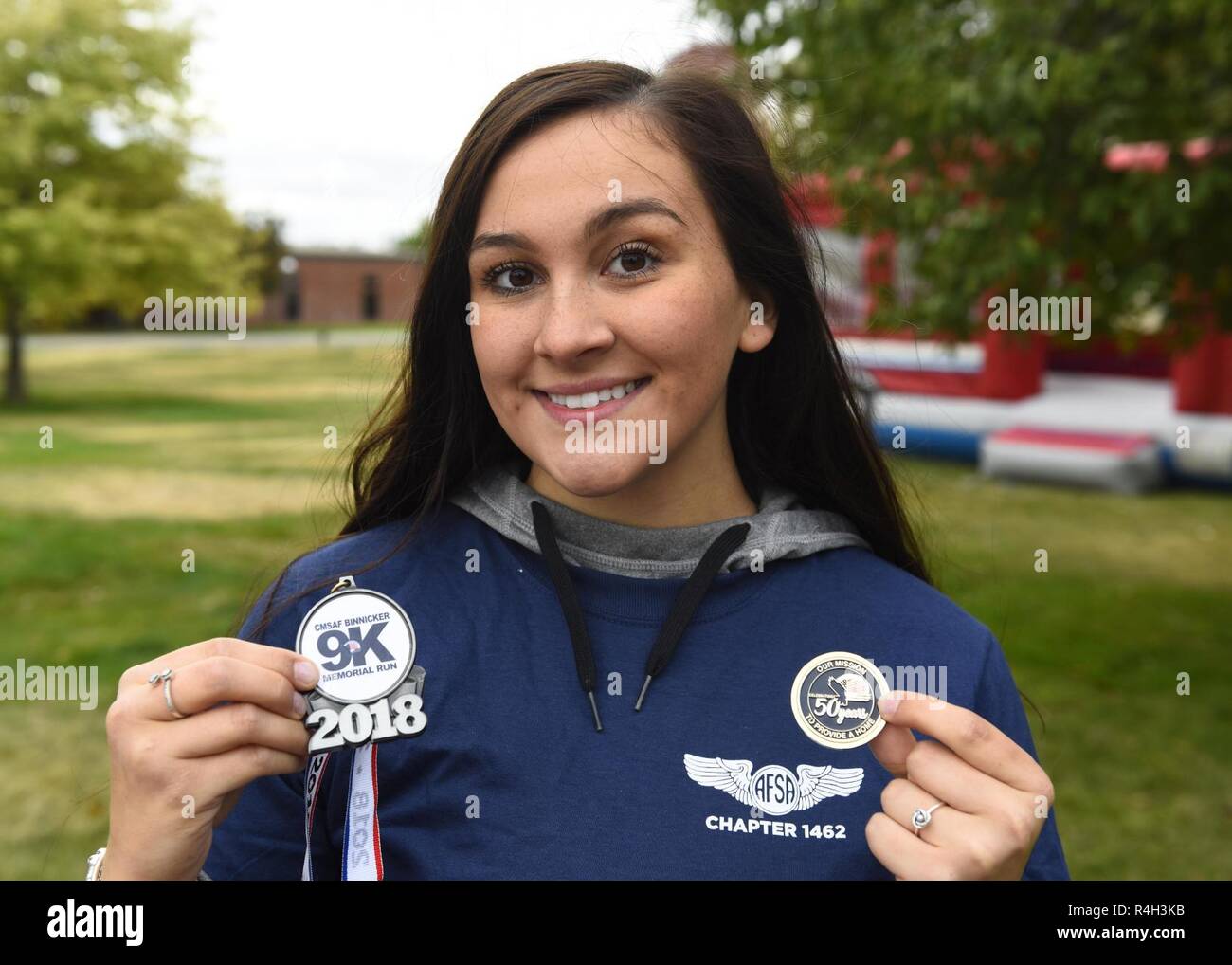 Airman Olivia Simione, 92nd Air Refueling Wing Religous Affairs chaplain assistant, poses with the CMSAF Binnicker 9K Memorial Run finisher's medallion and a 50th Anniversary Air Force Enlisted Village commemorative coin at Miller Park in Fairchild Air Force, Washington, Sept. 22, 2018. The AFEV is a nonprofit organization whose core mission is to provide a safe and secure home for survivng spouses of retired enlisted Airmen. Stock Photo