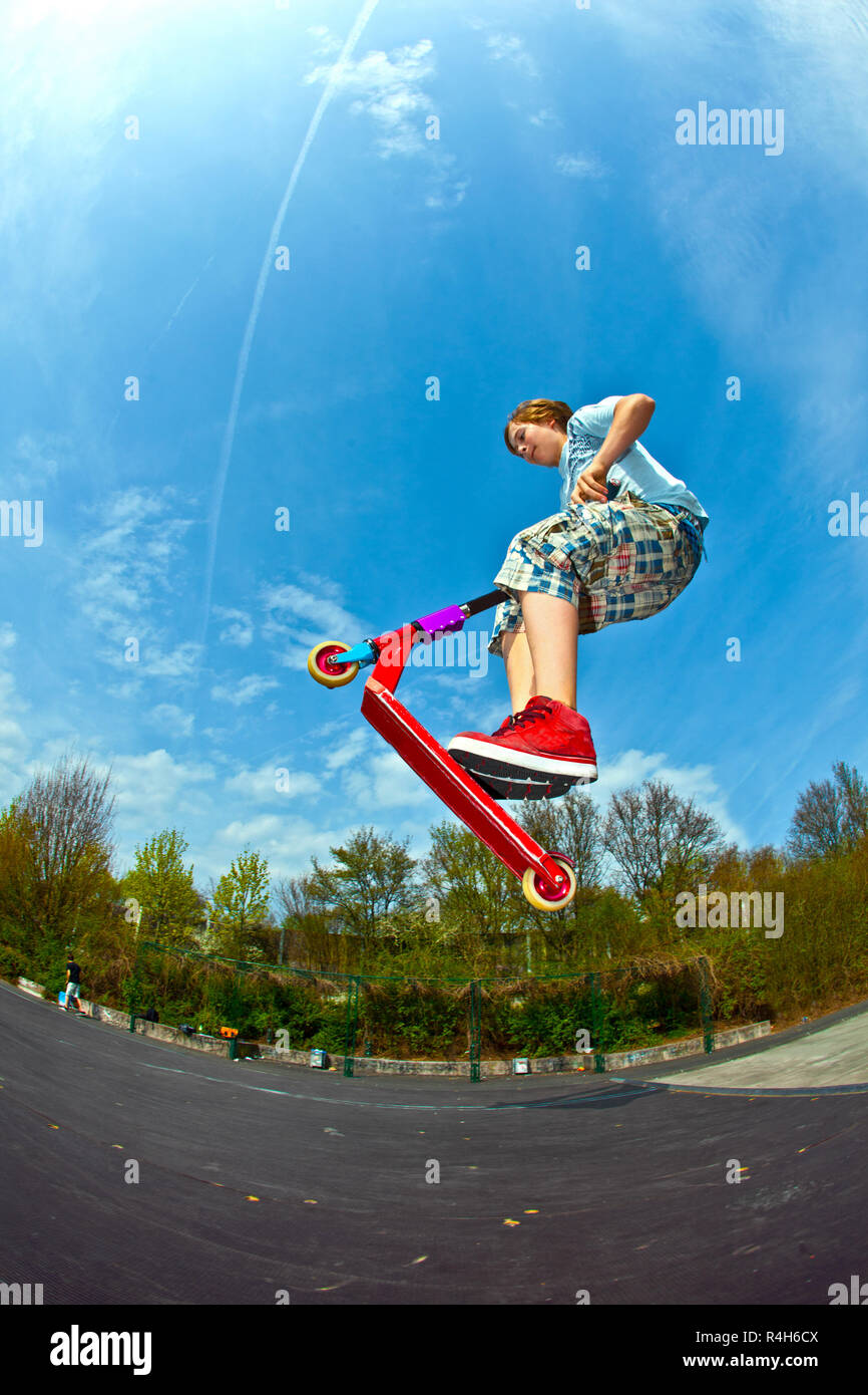boy is jumping with a scooter over a spine in the skate parc Stock ...