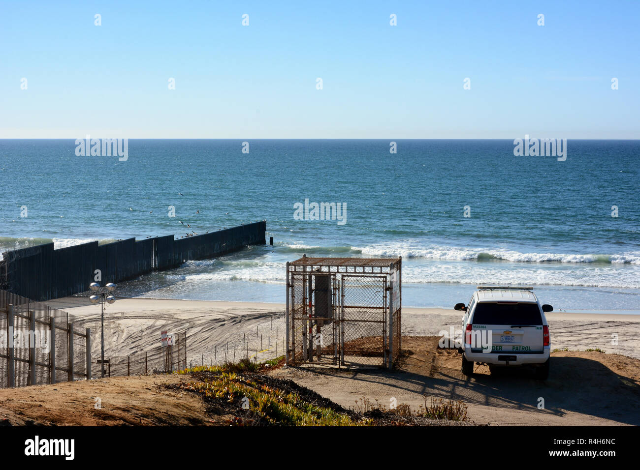 SAN YSIDRO, CALIFORNIA - NOVEMBER 26, 2018: A Border Patrol Vehicle watches over the beach and border wall that extends into the ocean, at Imperial Be Stock Photo