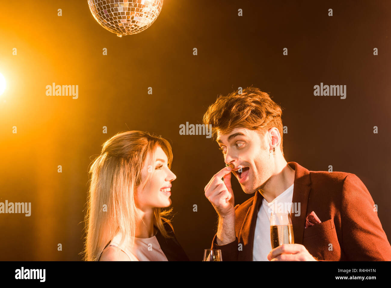 shot of happy flirting couple with champagne having fun during party under golden light Stock Photo - Alamy