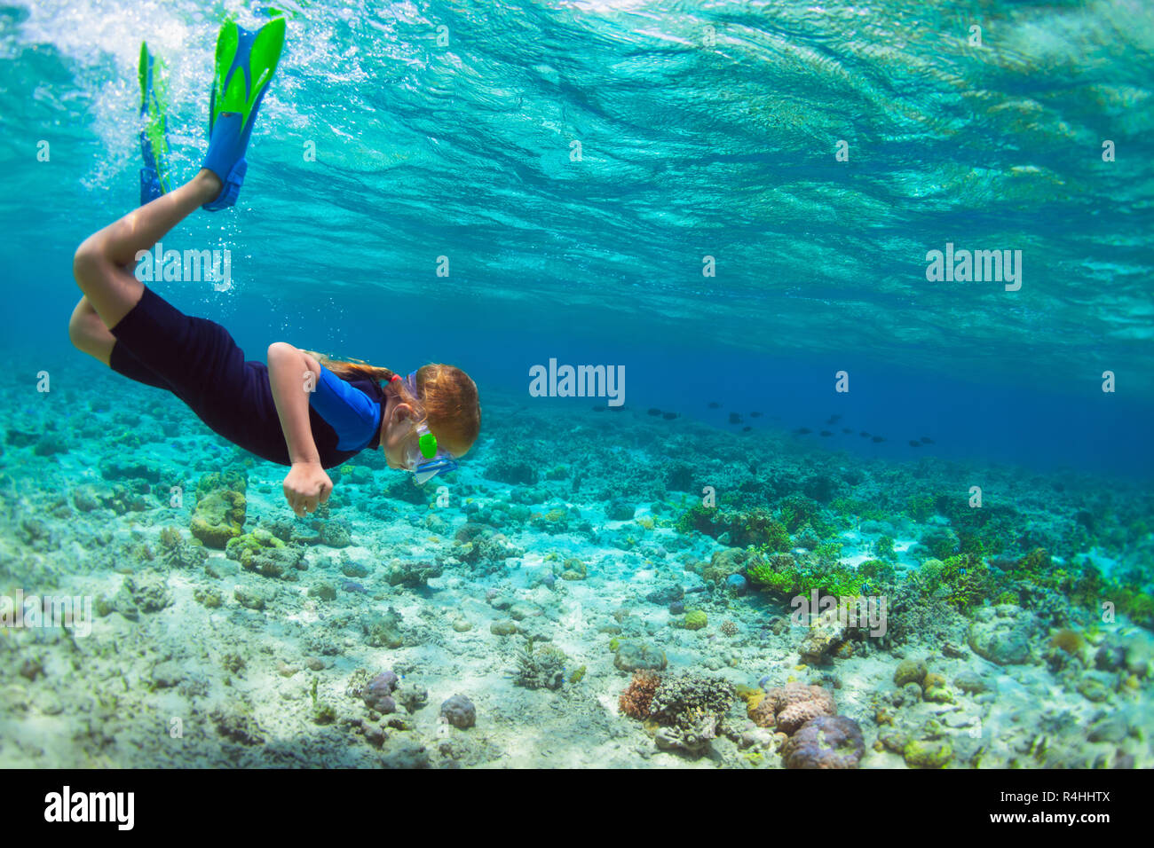 Happy little kid in snorkeling mask dive underwater with tropical fishes in coral reef sea lagoon. Family travel lifestyle in summer adventure camp. Stock Photo