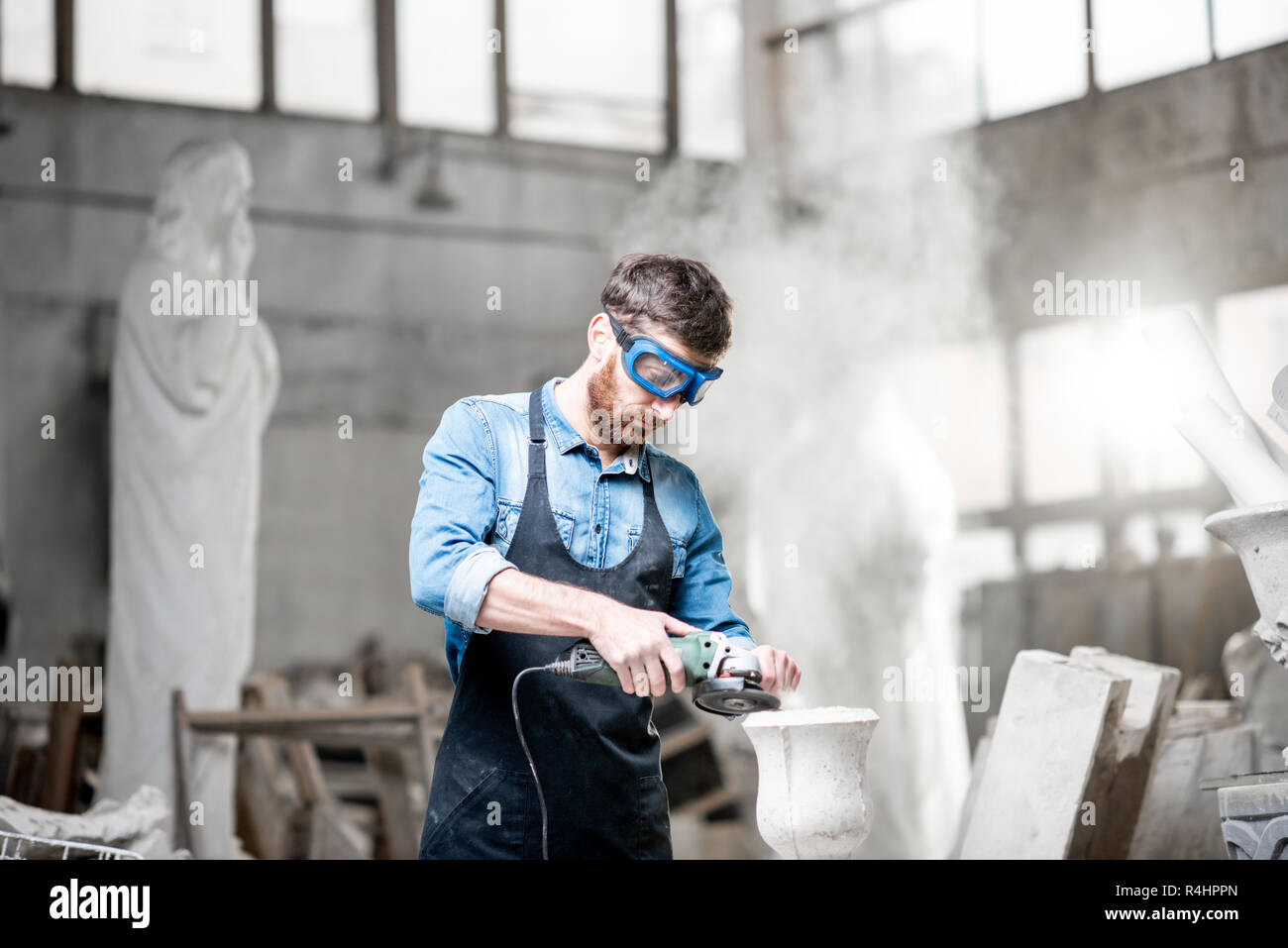 Sculptor in workware grinding stone vase at the working space in the old atmospheric studio Stock Photo