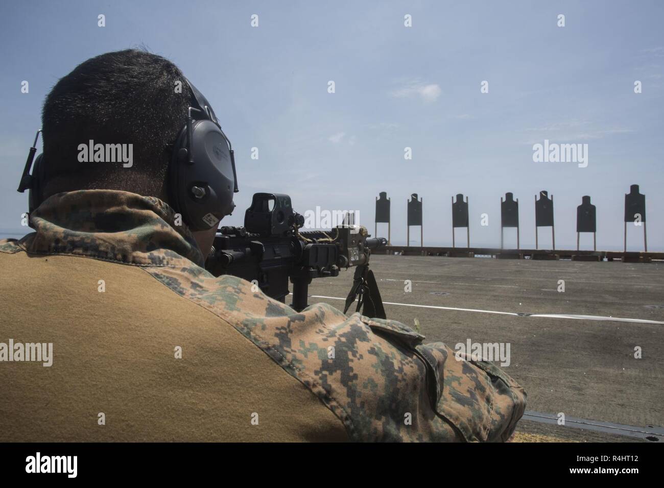 Gunnery Sgt. Jesus Cisneros Jr., the platoon sergeant for the 31st Marine Expeditionary Unit’s Amphibious Reconnaissance Platoon, aims an M4 carbine during marksmanship training aboard the amphibious assault ship USS Wasp (LHD 1), underway in the South China Sea, Sept. 30, 2018. Cisneros, a native of Lake Station, Indiana, graduated River Forest High School, May 1997; he enlisted in January 2004. While underway, Marines conduct live-fire exercises on the flight deck and in the hangar bay to refine marksmanship tactics and techniques. The 31st MEU, the Marine Corps' only continuously forward-de Stock Photo