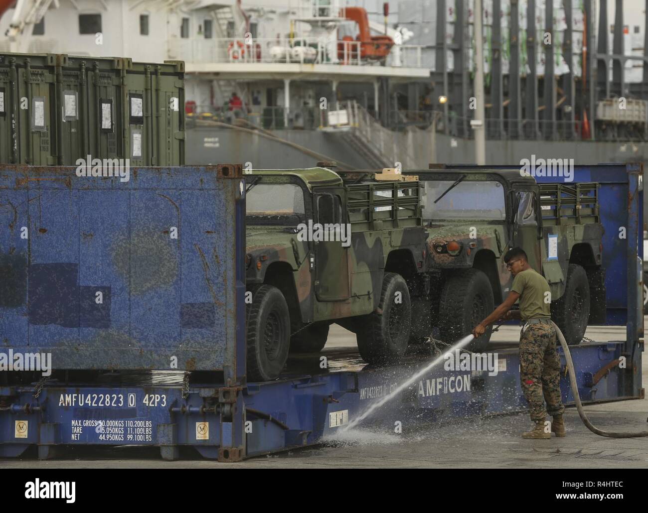 A U.S. Marine with II Marine Expeditionary Force sprays off a trailer before storing them on USNS Wright (T-AVB 3) before embarkation to Norway at the Port of Morehead City in Beaufort, N.C., Sept. 28, 2018. These vehicles will be used as part of II MEFs participation in the NATO-led Exercise Trident Juncture 18 in Norway, Sweden, Finland, and Iceland. Trident Juncture 18 enhances the U.S. and NATO Allies’ abilities to work together collectively to conduct military operations under challenging conditions. Trident Juncture will include more than 14,000 U.S. service members and 31 Allied and par Stock Photo