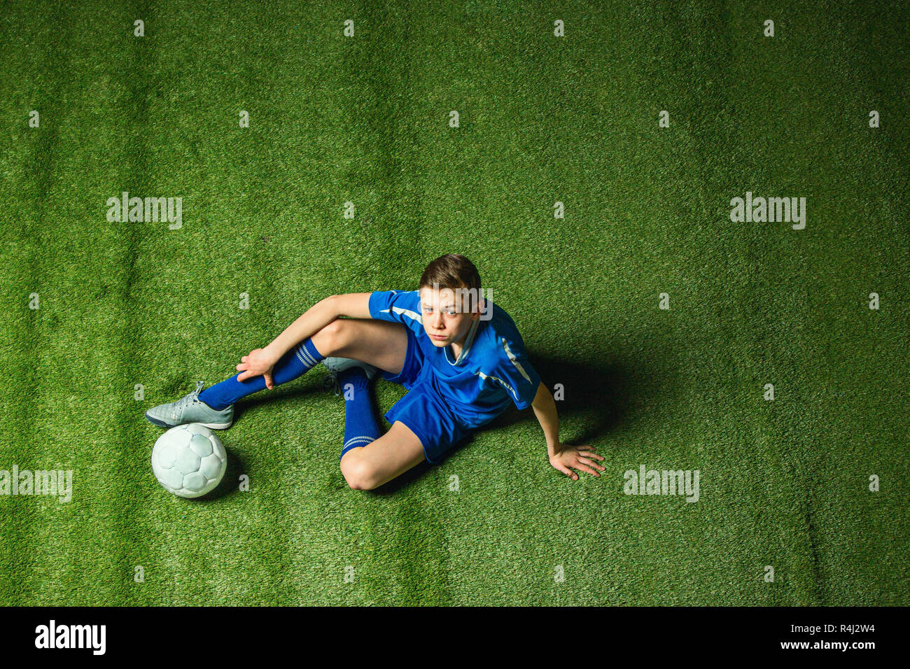 Boy soccer player sitting on greeb grass Stock Photo
