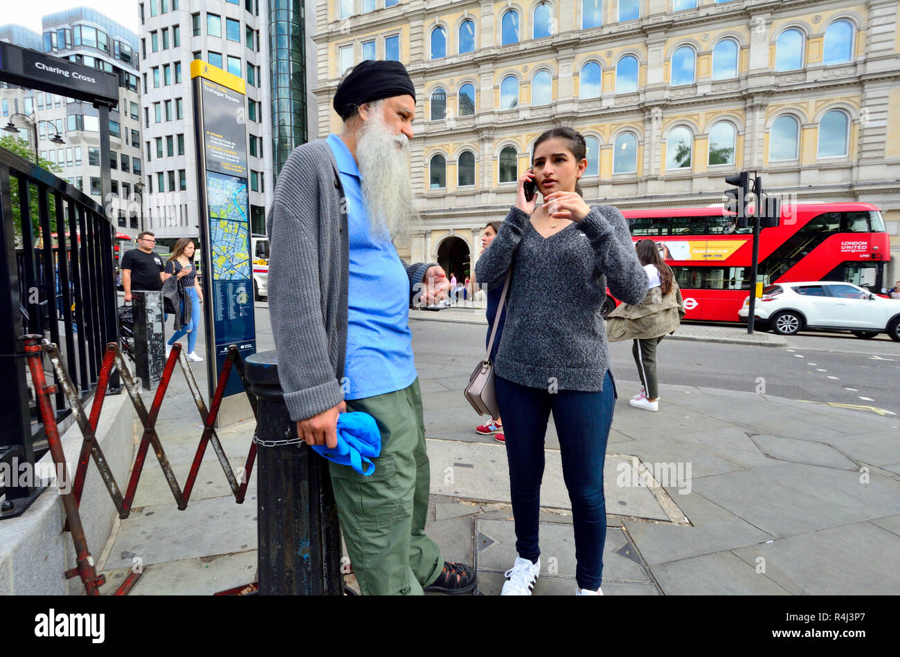 Young Asian woman on her mobile phone in Trafalgar Square, with an older man (father?) London, England, UK. Stock Photo