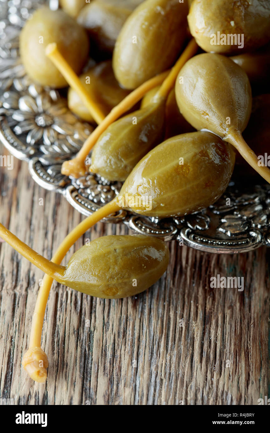 Pickled caper berries in metal dish . Edible fruits of Capparis