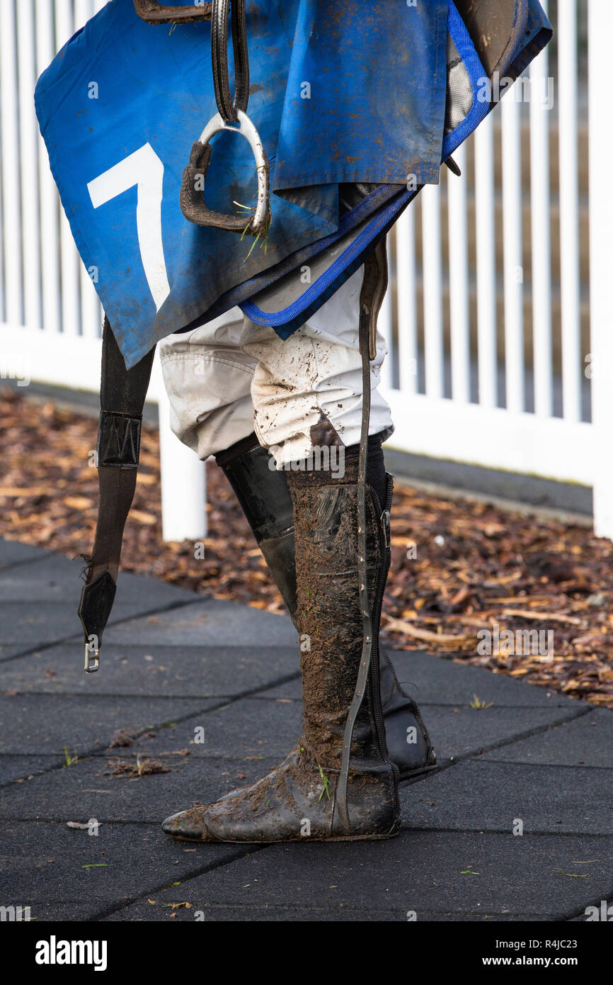 A horse racing jockey's muddy boots and stirrup, with number 7, after a race Stock Photo