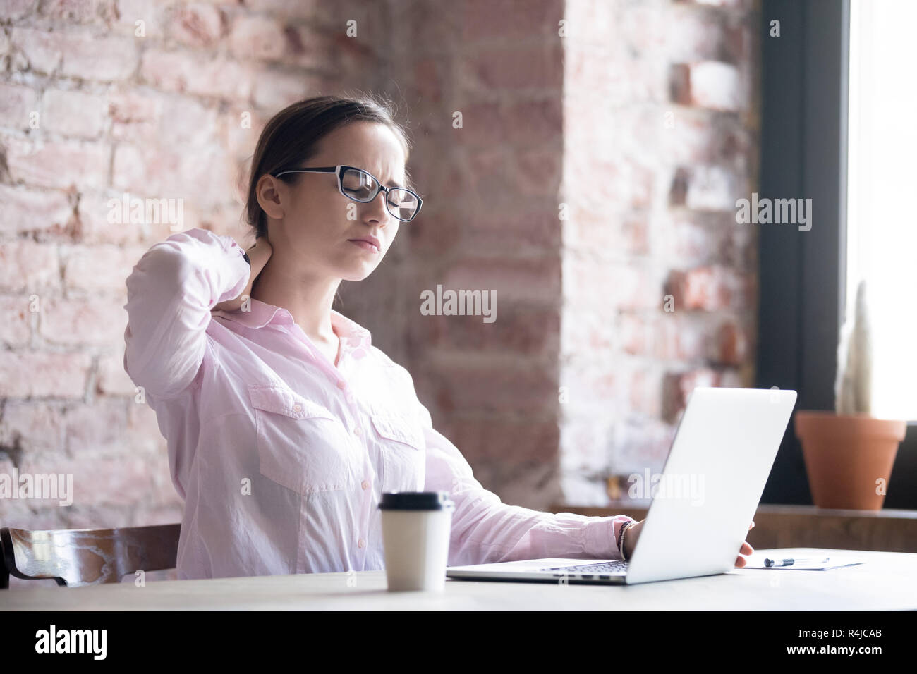 Tired businesswoman massaging strained neck muscles at workplace Stock ...