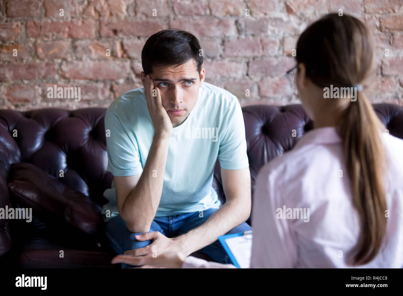 Unhappy male patient listening to a psychologist counselor. Stock Photo