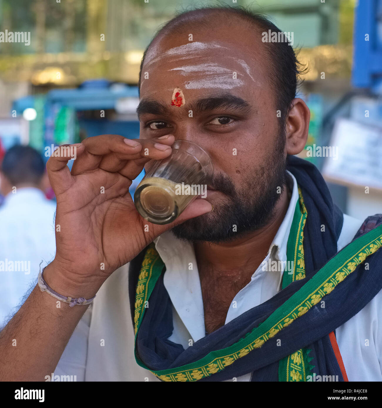 A South Indian man drinking tea at a roadside tea stall in Mumbai, India, drinking from a typical small Indian tea glass Stock Photo