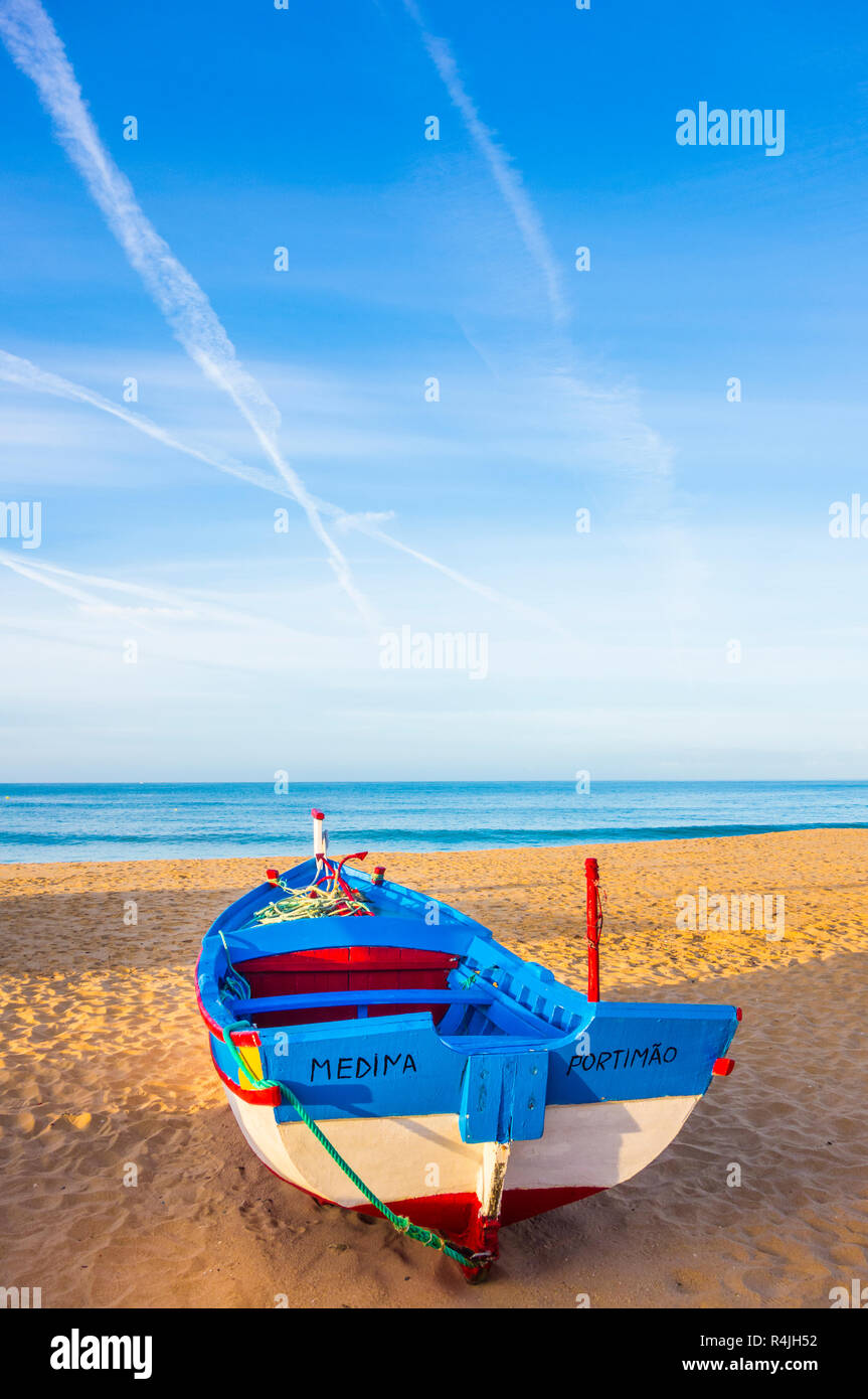 traditionally painted fishing boat on the beach at dusk Stock Photo
