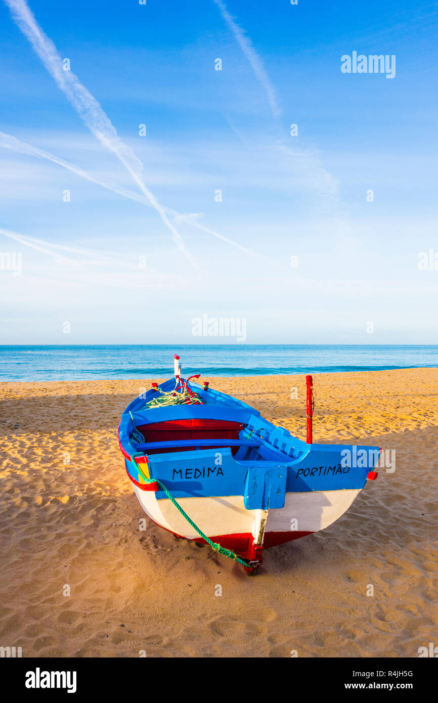 traditionally painted fishing boat on the beach at dusk, armacao de pera, algarve, portugal Stock Photo