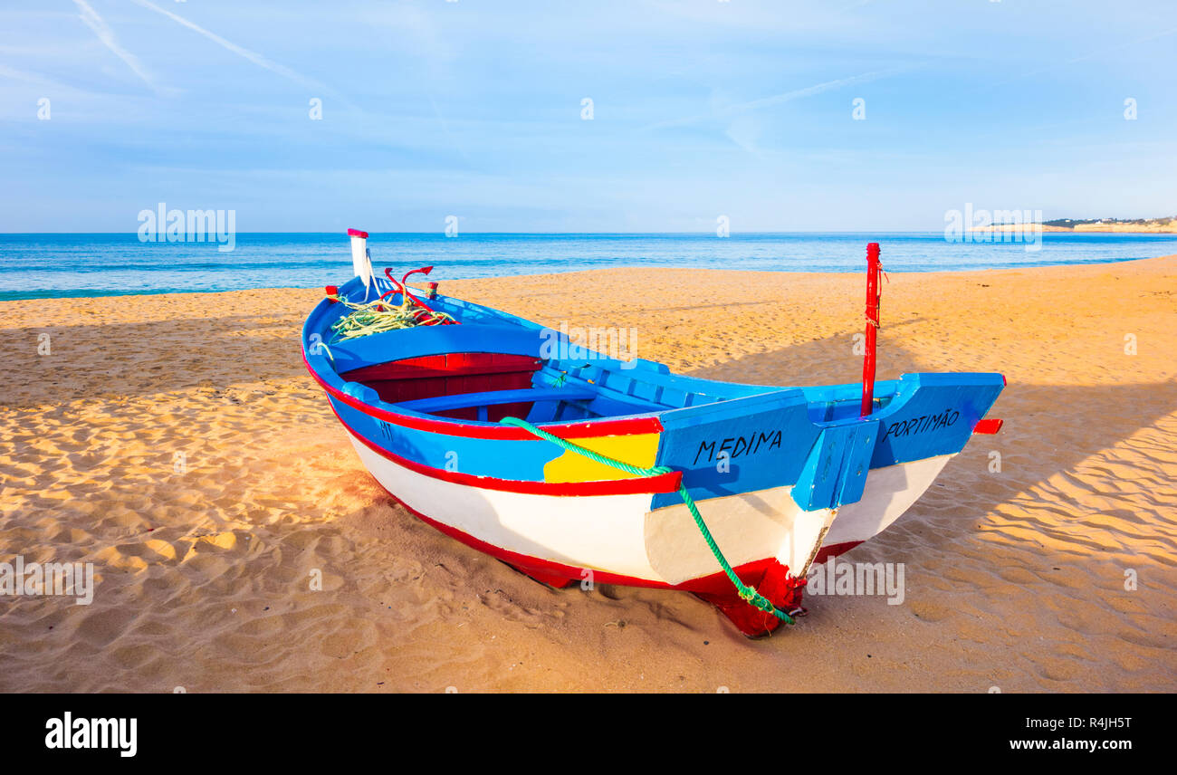 traditionally painted fishing boat on the beach at dusk, armacao de pera, algarve, portugal Stock Photo
