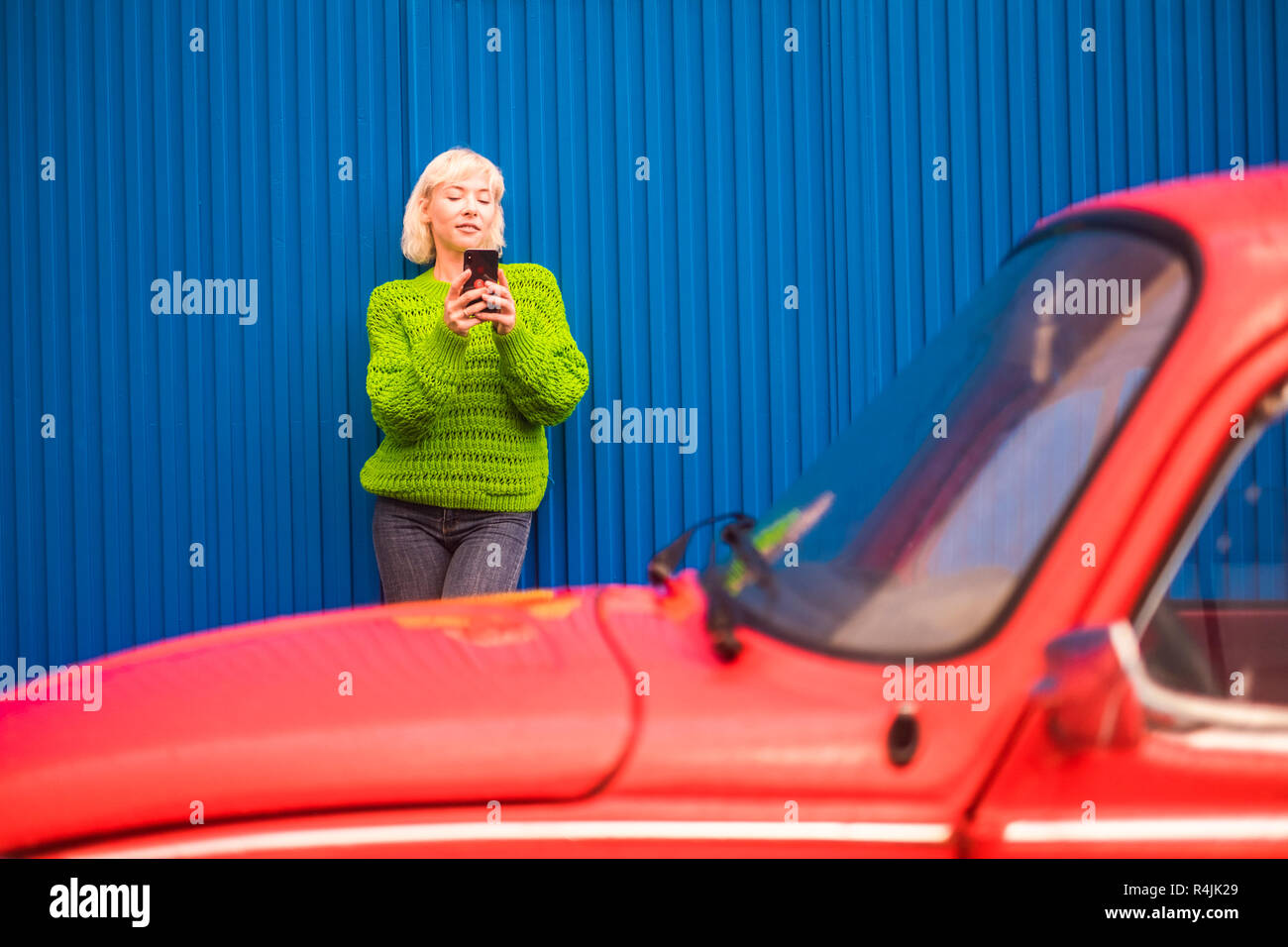 Fashion Coloured Concept Image With Blonde Caucasian Girl Standing Near A Red Vintage Old Car With Blue Steel Wall In Backgorund Urban And Colors Wit Stock Photo Alamy