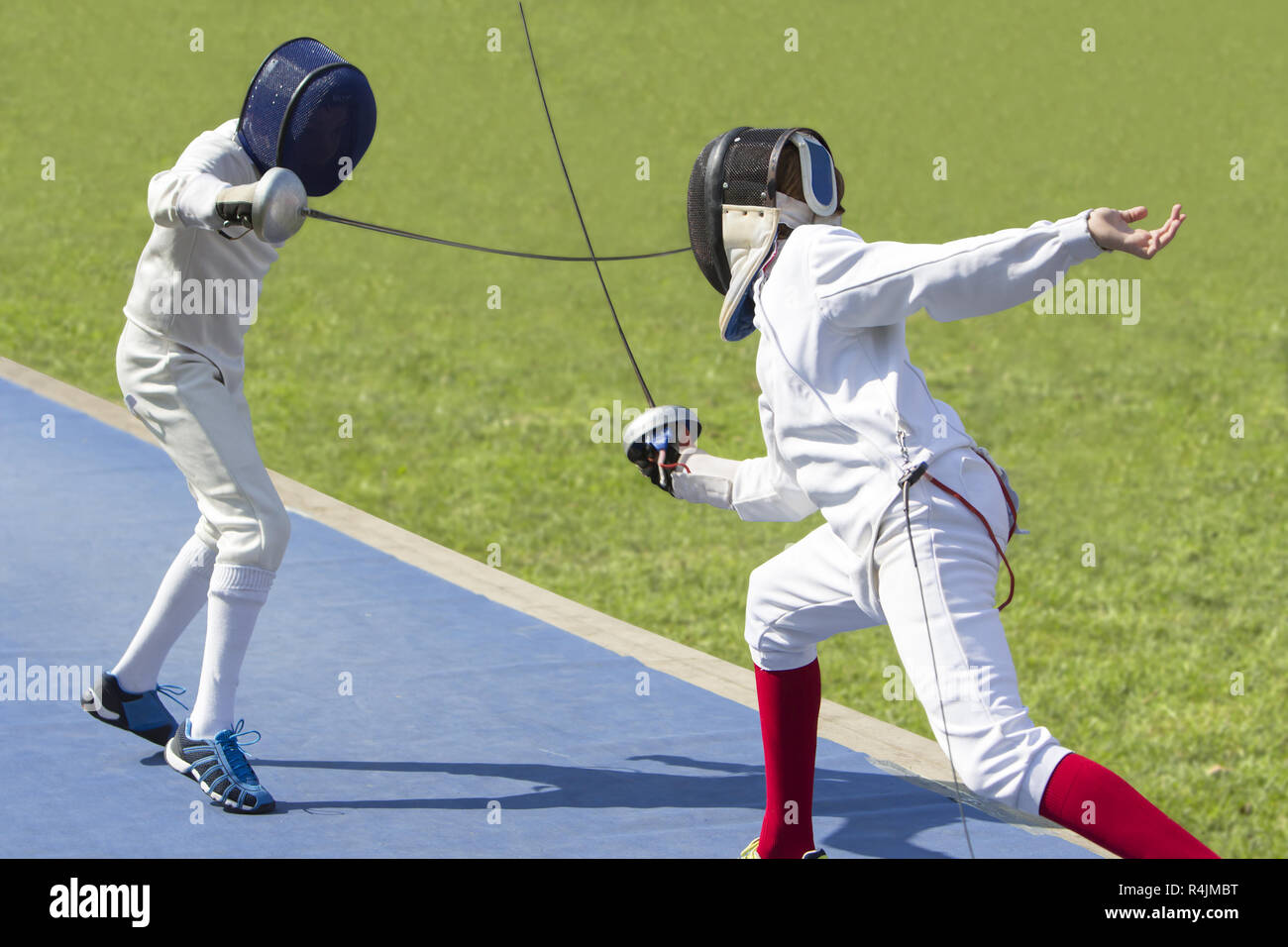 Two young man fencing athletes fight on outdoor playground Stock Photo