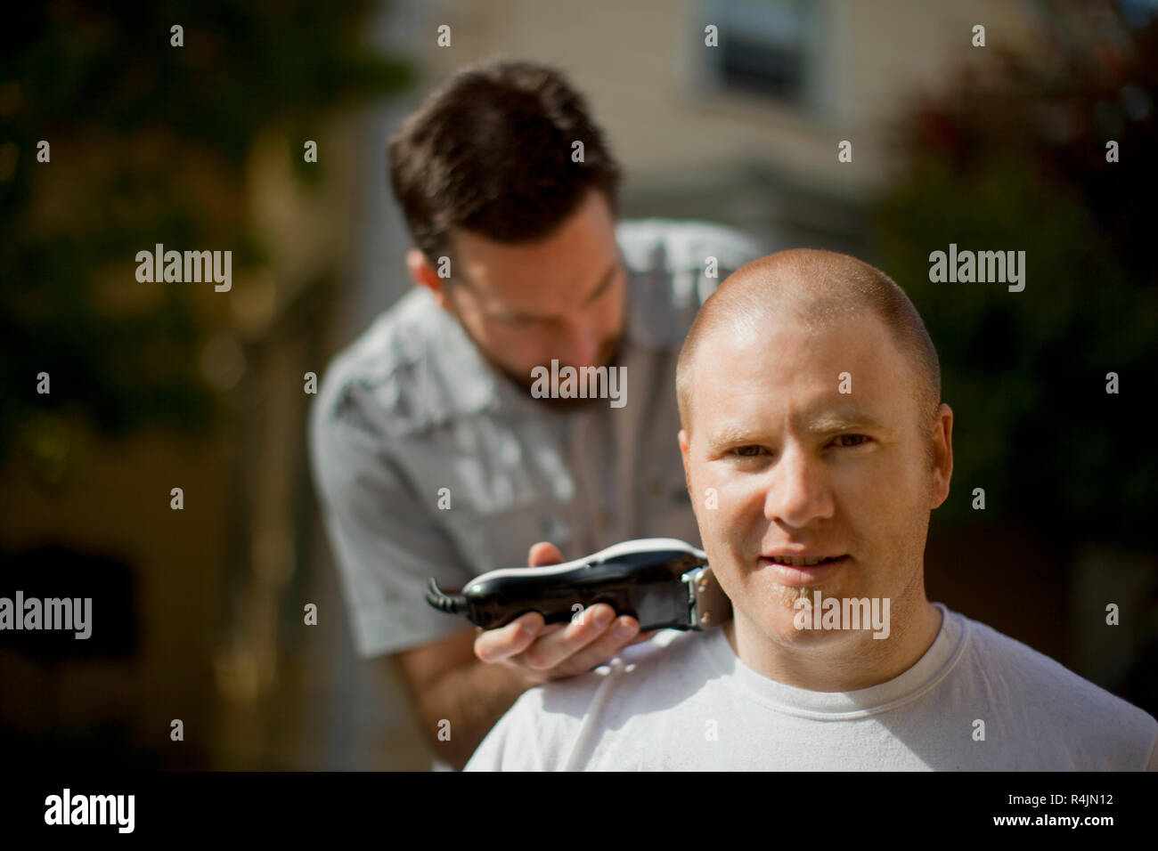 Man shaving another man's head. Stock Photo
