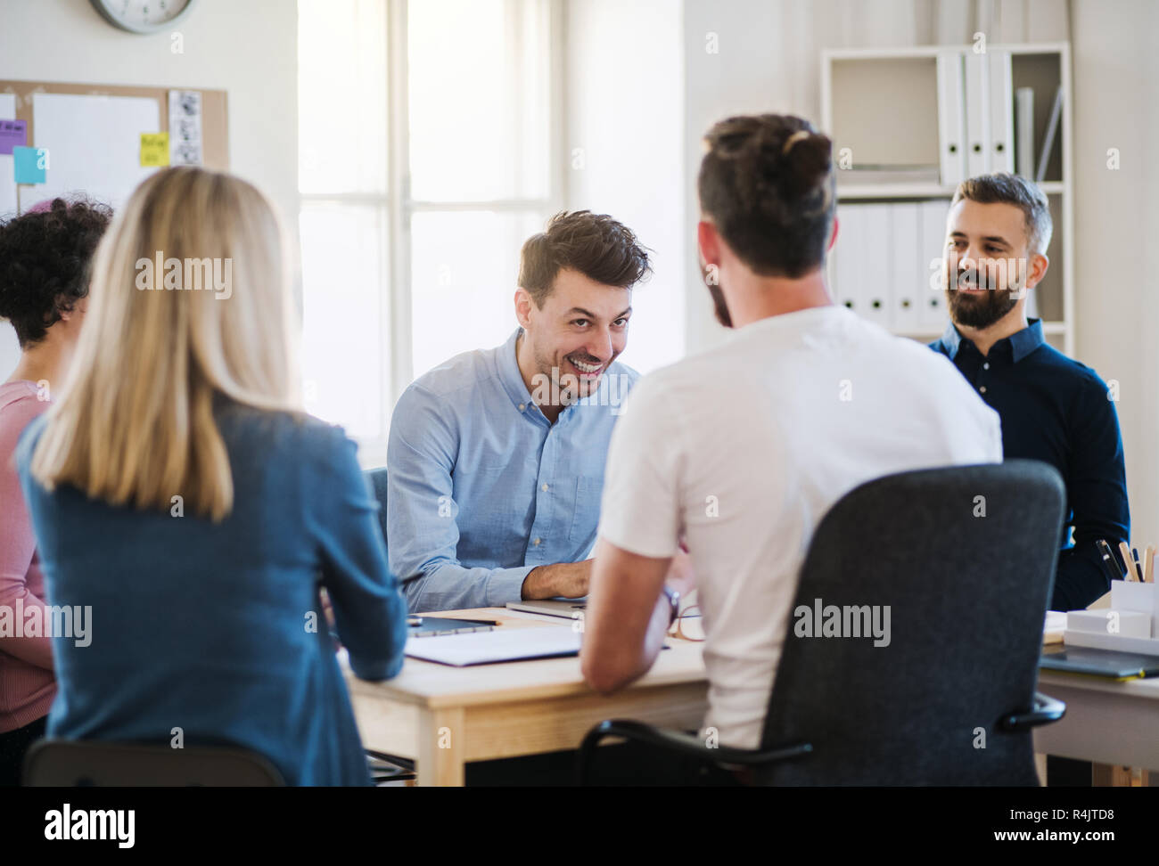 Group of young businesspeople sitting around table in a modern office ...