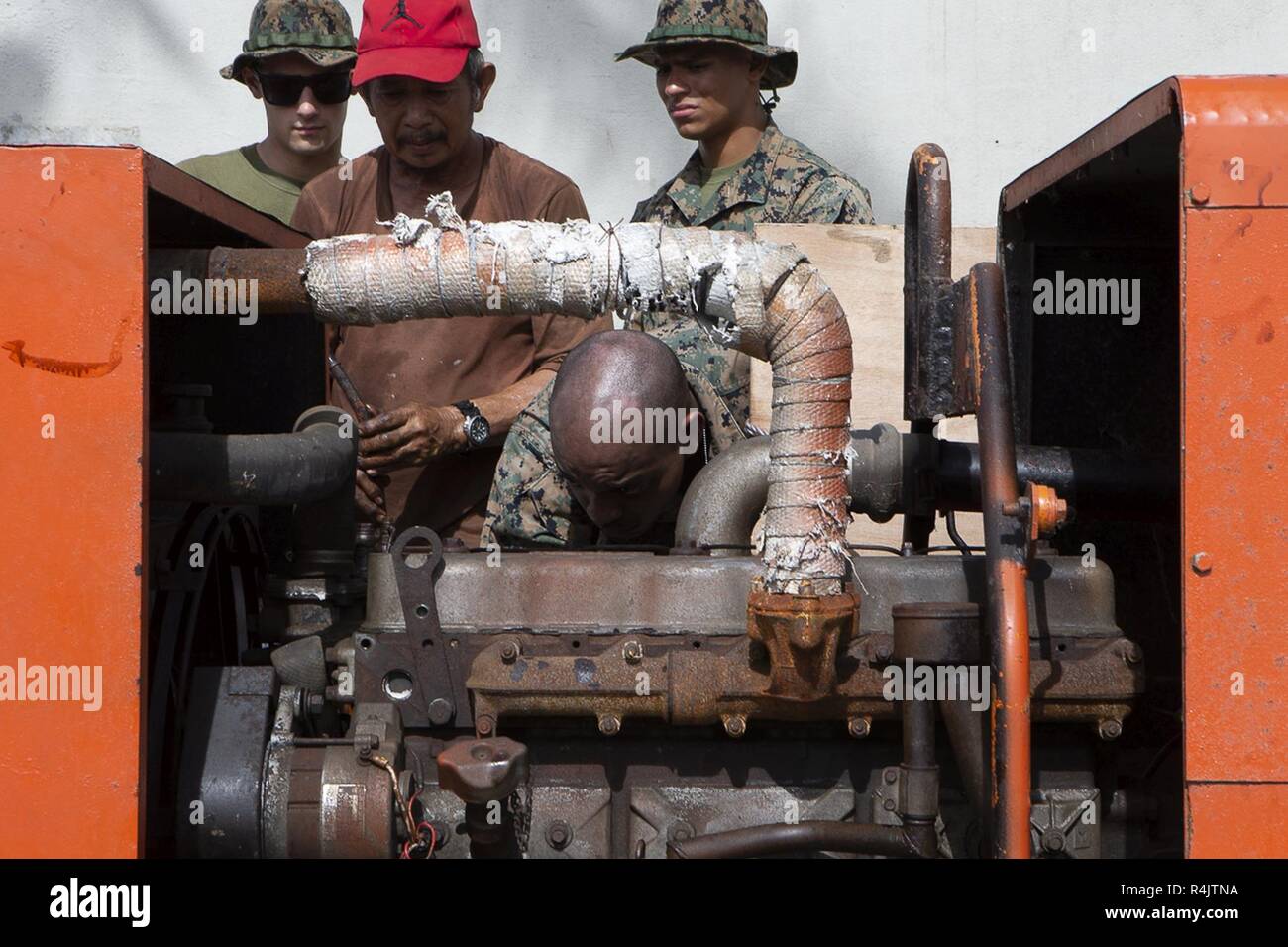 Marines with Combat Logistics Battalion 31 help repair a generator with a local at the gas station on Tinian, Commonwealth of the Northern Mariana Islands, Nov. 1, 2018. Businesses, government buildings, homes and schools were heavily damaged by Super Typhoon Yutu, which made a direct hit with devastating effect on Tinian Oct. 25 packing 170 MPH winds – it is the second strongest storm to ever hit U.S. soil and the strongest storm of 2018. Marines with the 31st Marine Expeditionary Unit and CLB-31 arrived on Tinian Oct. 29-31 in the wake of Super Typhoon Yutu as part of the U.S. Defense Suppor Stock Photo