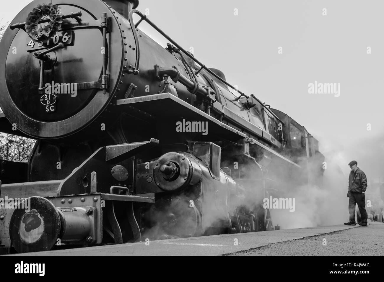 Mono, low angle, close up of vintage UK steam locomotive with trainspotter, rail enthusiast on platform, Severn Valley Heritage Railway. Stock Photo