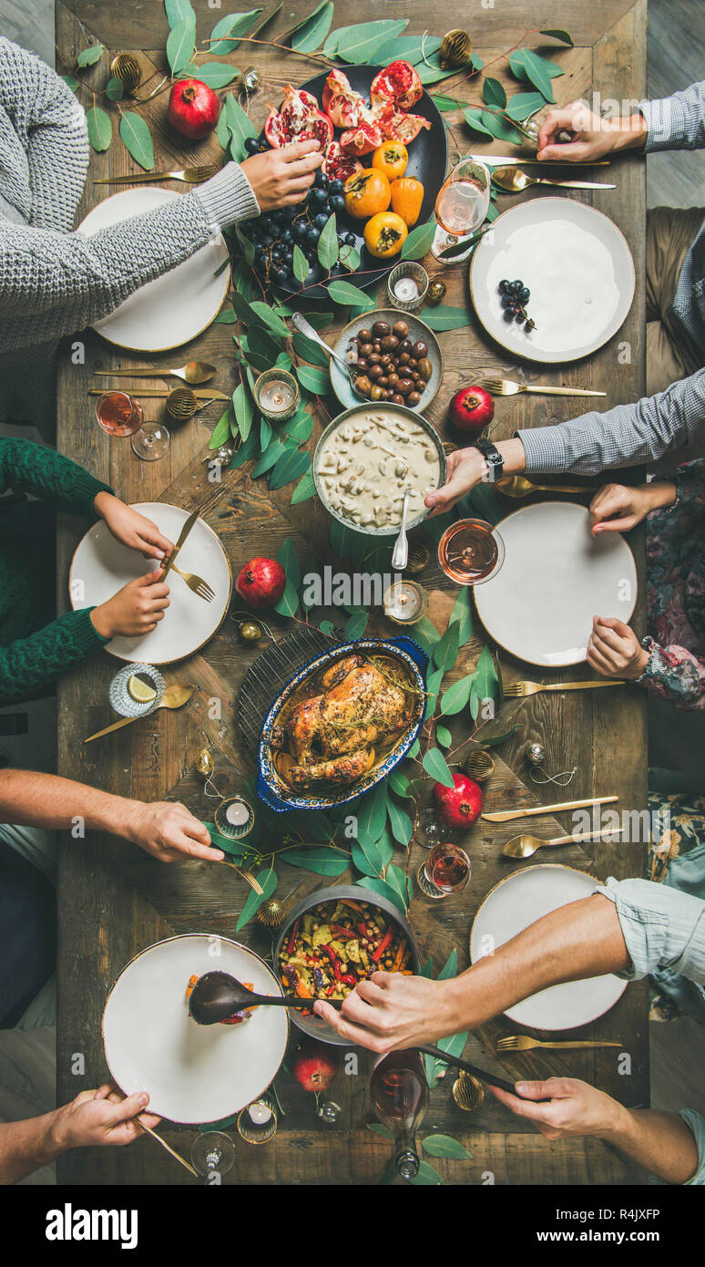 Company of friends or family gathering for Christmas or New Year party dinner at festive table. Flat-lay of people eating different meals and celebrat Stock Photo