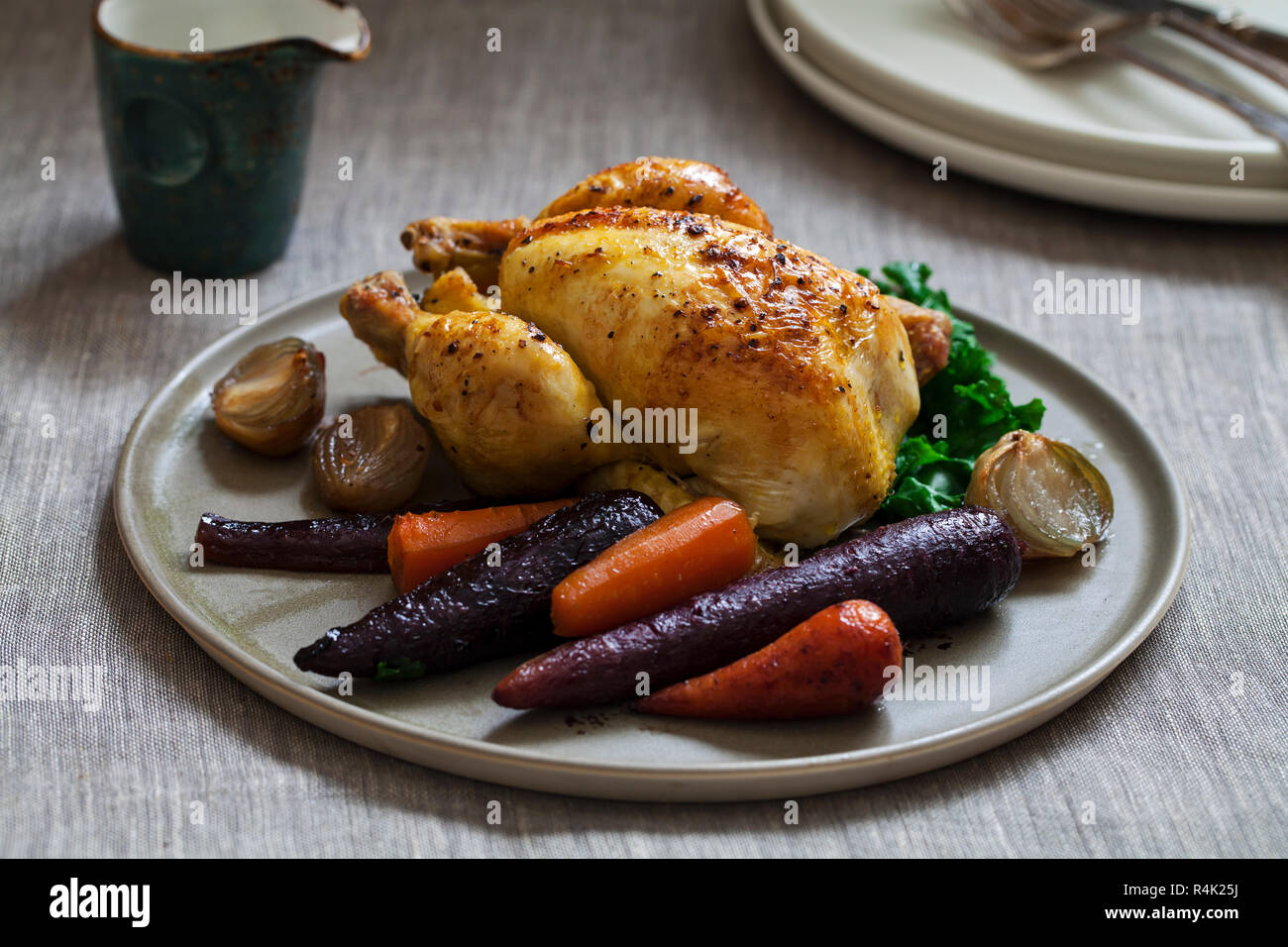 Whole roast poussin with purple and red carrot, kale, braised shallots and gravy Stock Photo