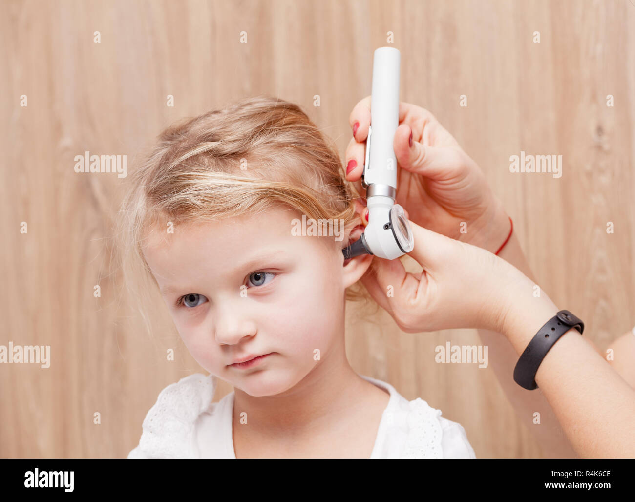 Female pediatrician examines little girl's ear. Doctor using a otoscope