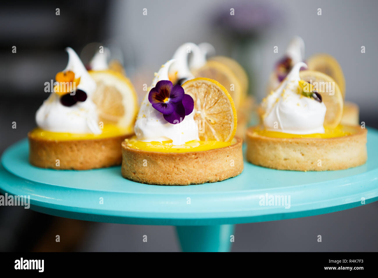 Tasty little creamy cupcakes with lemon slice and white cream served on plate in Italian restaurant. Delicious little cakes for dessert in bakery cafe Stock Photo