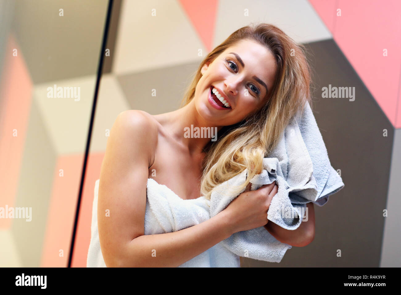 Beautiful blonde Caucasian woman posing in bathroom with wet hair Stock Photo