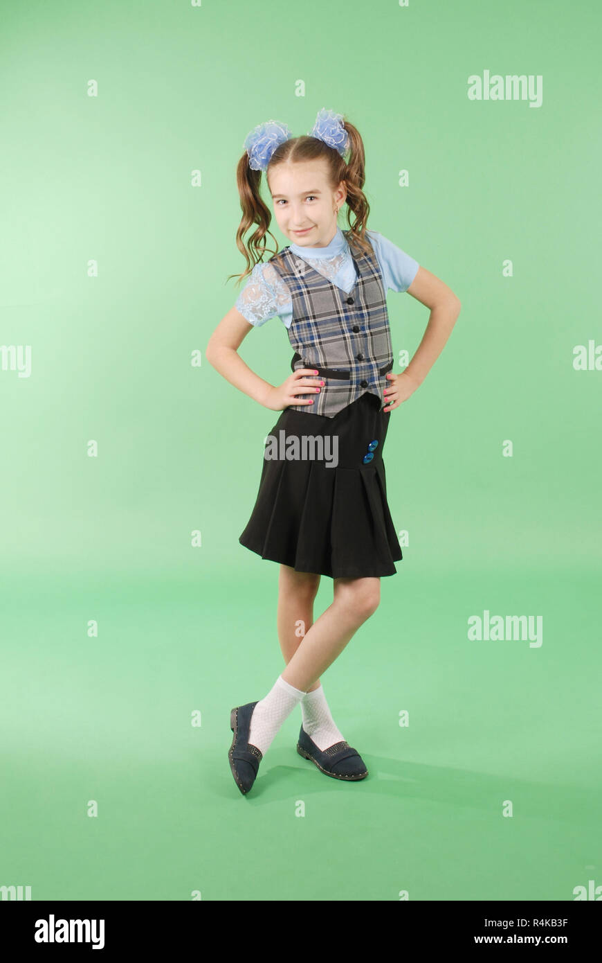 Beautiful young girl in school uniform isolated on green background