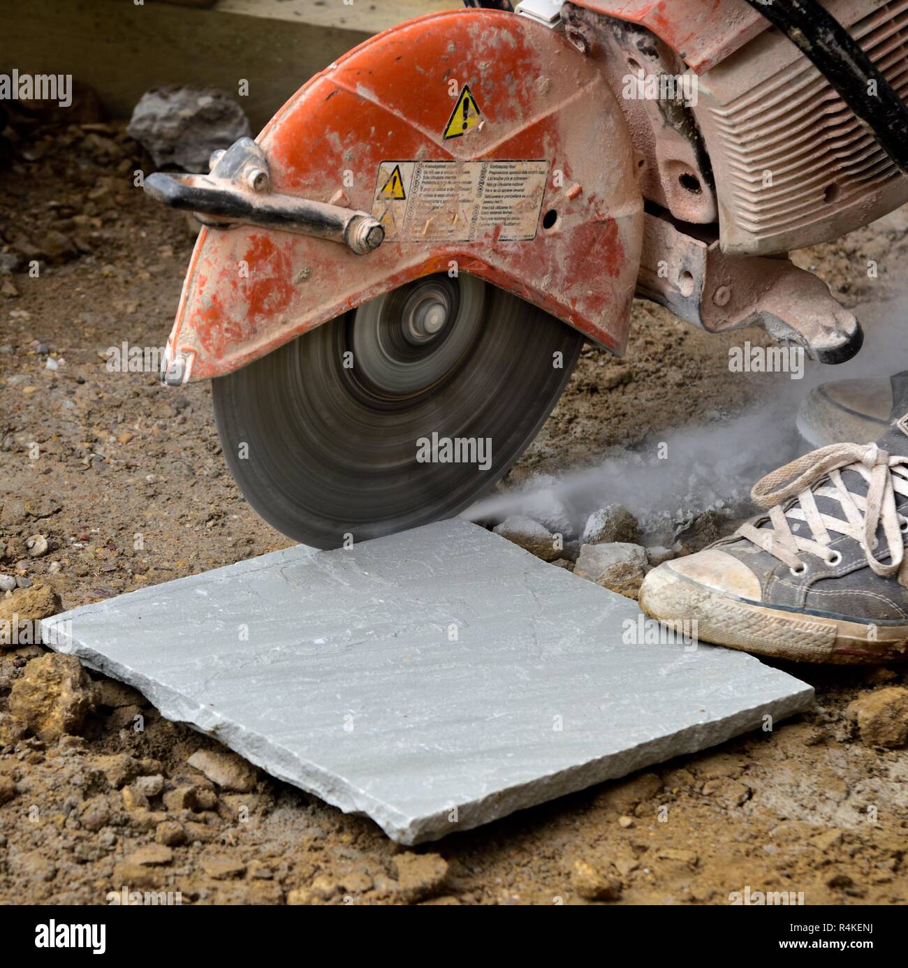 Stone paving slab being cut with a circular petrol powered saw Stock Photo