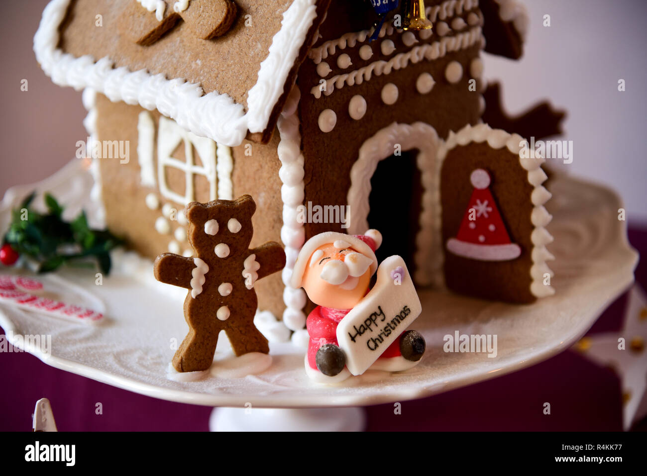 Christmas gingerbread house with Santa and a teddy bear with white icing Stock Photo