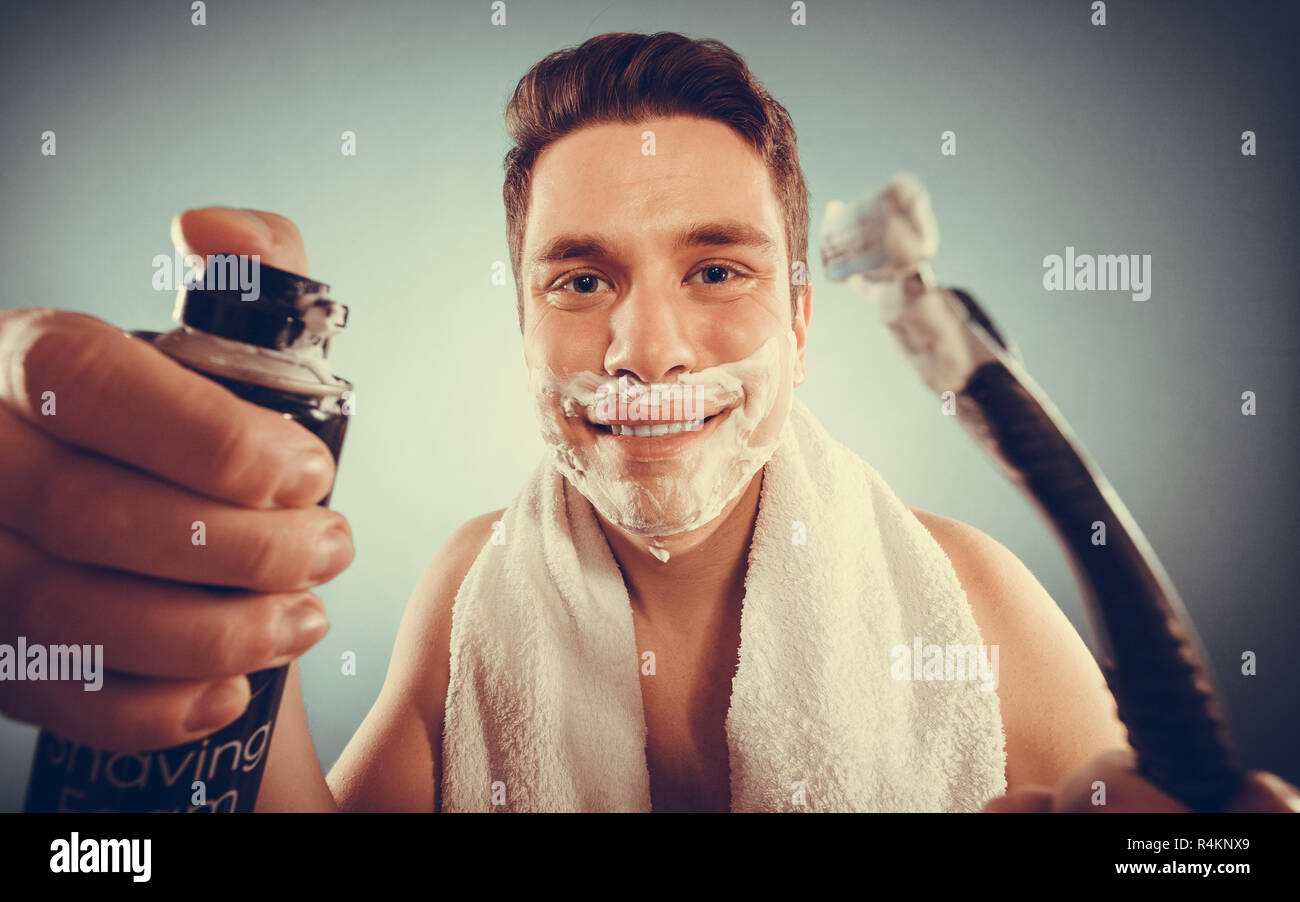Handsome bearded young man with shaving cream foam can and razor