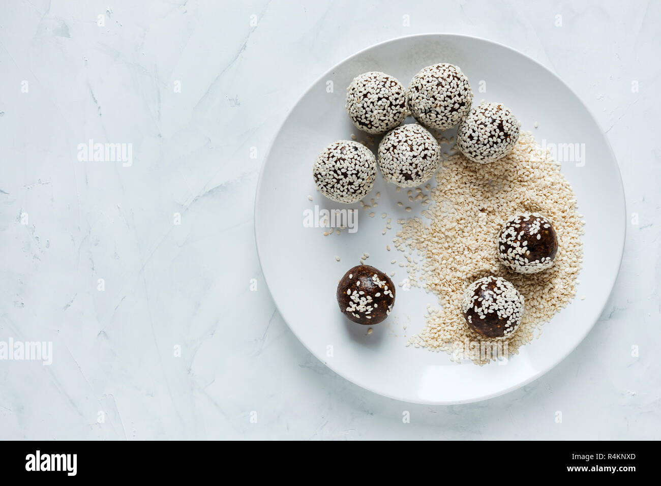 Top view of white plate with preparing energy ball in sesame seeds Stock Photo