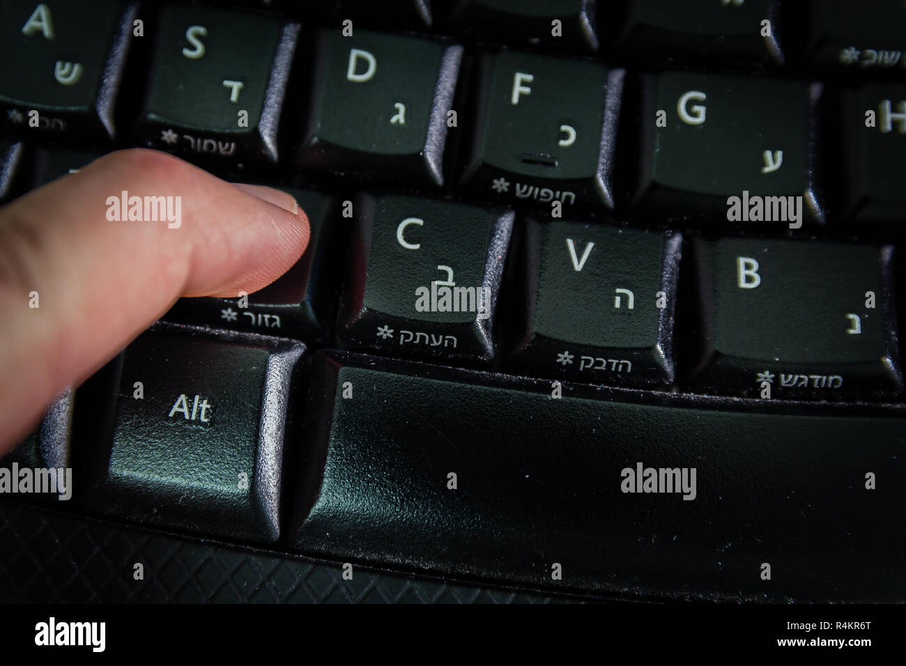 Man typing on a keyboard with letters in Hebrew and English Stock Photo