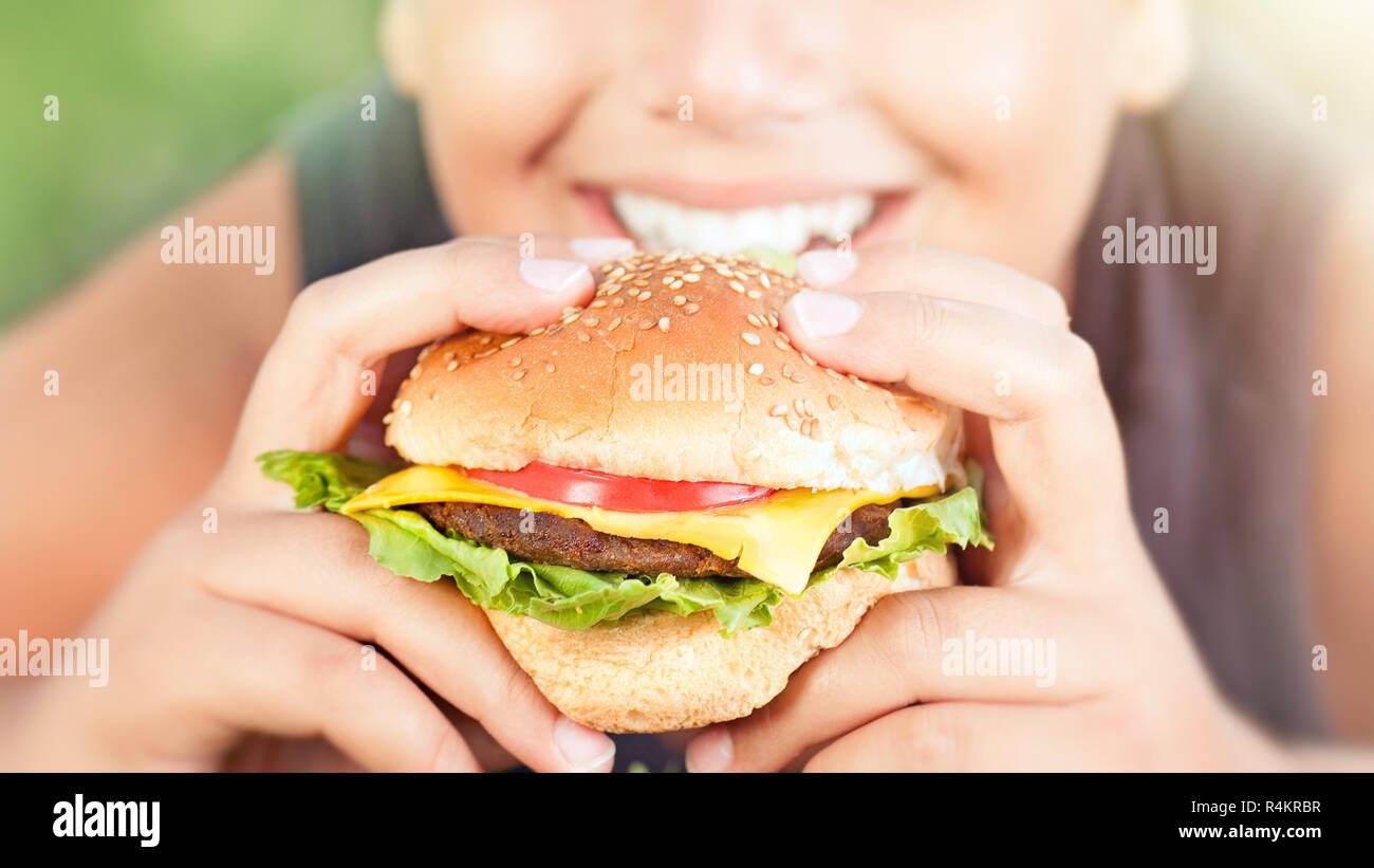Happy teen boy eating burger Stock Photo
