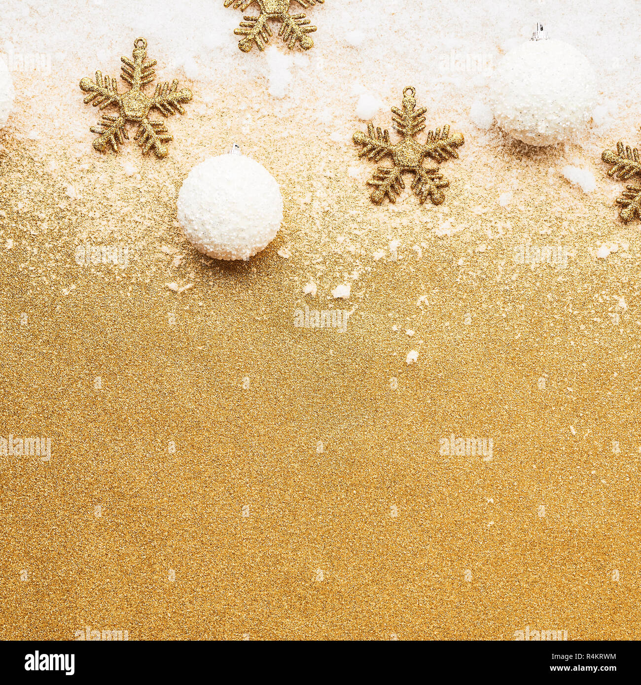 Beautiful christmas silver and white deco baubles with golden snowflake deco over powdery snow on golden glitter background. Flat lay design. Copy Spa Stock Photo